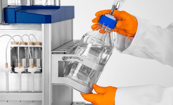 Naukowiec w kitlu laboratoryjnym obserwujący monitor urządzenia do chromatografii gazowej (GC-MS), analizujący próbki e-liquidu.